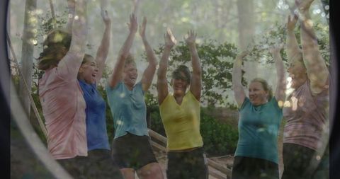 Women raising arms in group fitness gathering outdoors