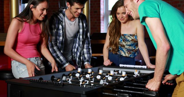 Friends Enjoying Competitive Foosball Game at Recreation Hall - Download Free Stock Images Pikwizard.com