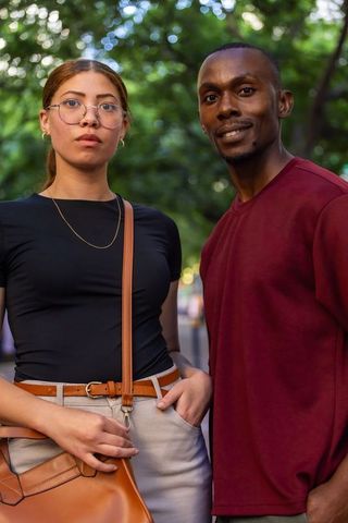 Young mixed-race woman and black man standing together on urban park path at golden hour