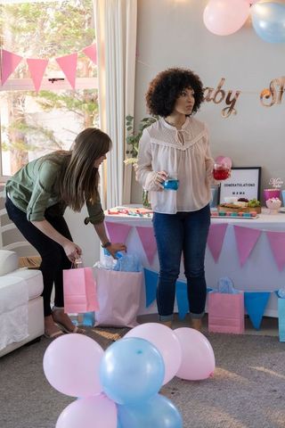 Friends preparing drinks at baby shower with pastel decorations