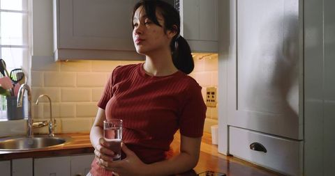 Woman Relaxing in Modern Kitchen with Glass of Water