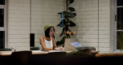Young woman working late on laptop in minimalist office