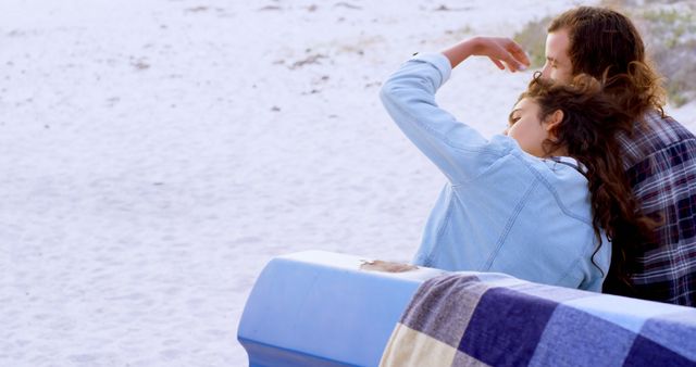 Young couple sitting on a boat at a sandy beach, relaxing and enjoying the serene waterfront scenery. Ideal for advertisements about summer vacations, romantic getaways, leisure, and lifestyle blogs.