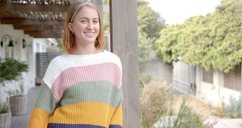 Smiling woman relaxing on rustic pergola porch with floral garden view