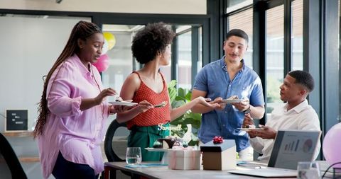 Joyful farewell party with multiracial colleagues sharing cake