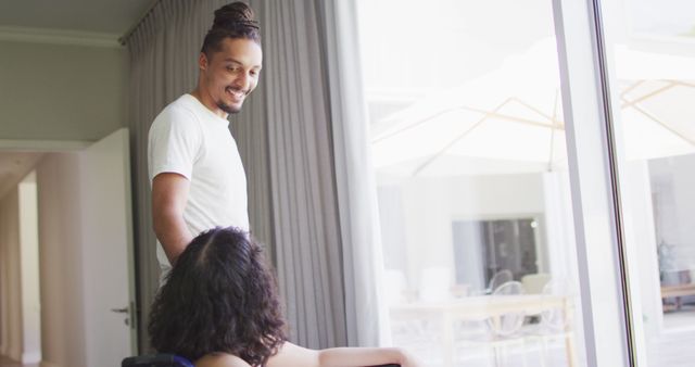 Happy Caregiver Interacting with Young Woman in Wheelchair Near Window - Download Free Stock Images Pikwizard.com