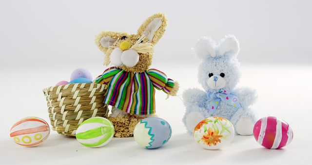 Two plush Easter bunnies, one brown and one blue, are positioned next to a basket filled with colorful Easter eggs, with copy space. The festive setup evokes the joy and tradition of Easter celebrations.