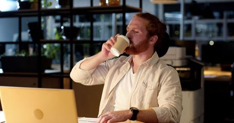 Red-Haired Professional Drinking Coffee While Working Late