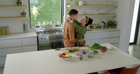 Couple Embracing During Meal Prep in Modern Minimalist Kitchen