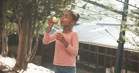 Child joyously blowing soap bubbles outdoors