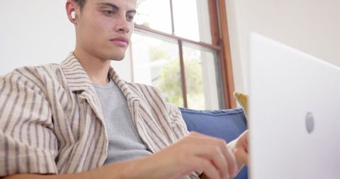 Man Wearing Earphones Using Laptop in Modern Home
