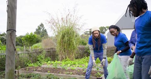 Volunteers digging raised beds and collecting green waste in community garden
