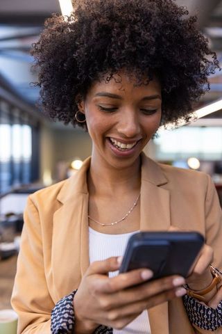 Smiling business professional using smartphone in modern office
