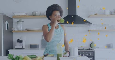 Woman sipping green smoothie in minimalist kitchen while preparing healthy morning routine