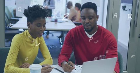 Young professionals collaborating and reviewing documents over laptop in modern bright office