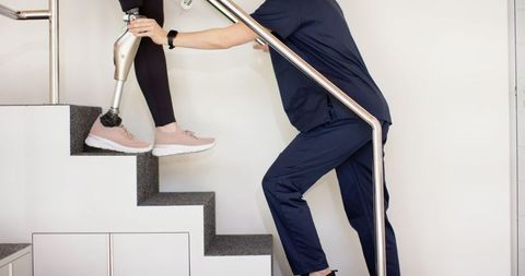 Therapist assisting woman with prosthetic leg in rehabilitation