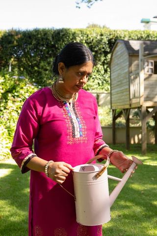 Woman Holding Watering Can in Lush Garden Landscape