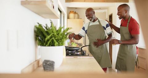 African american father and son enjoy cooking together in modern kitchen