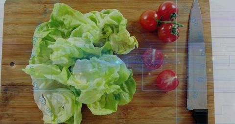 Butterhead lettuce with cherry tomatoes on wooden board and knife with blue tech overlay