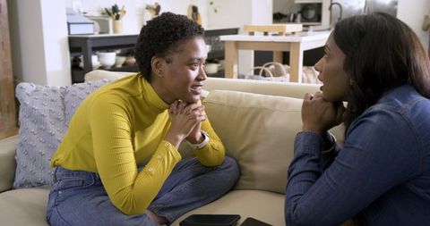 Two Diverse Women Engaged in Friendly Conversation on Sofa