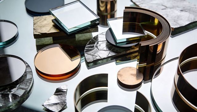 Stacking glass squares and amber green discs on mirrored surface with bronze arc accents