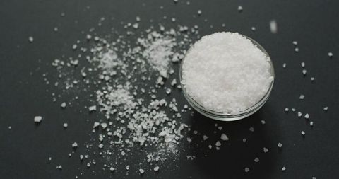 Coarse Sea Salt in Glass Bowl on Black Surface