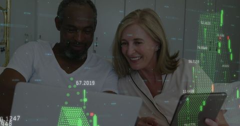 Diverse Couple Analyzing Financial Data on Laptop and Tablet