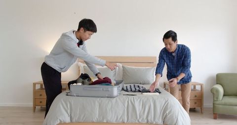 Father and Son Packing Suitcase for Vacation in Bedroom