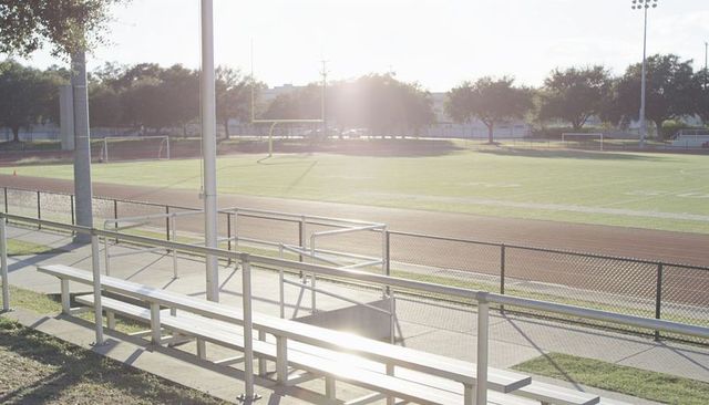 Bleachers reflecting sunlight at empty football field and running track
