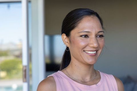 Smiling african american woman on pool patio wearing pink tank top and layered necklaces