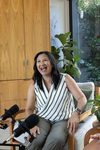 Laughing host recording relaxed home podcast interview in modern living room studio