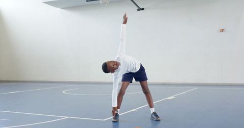 Young athlete stretching on indoor basketball court