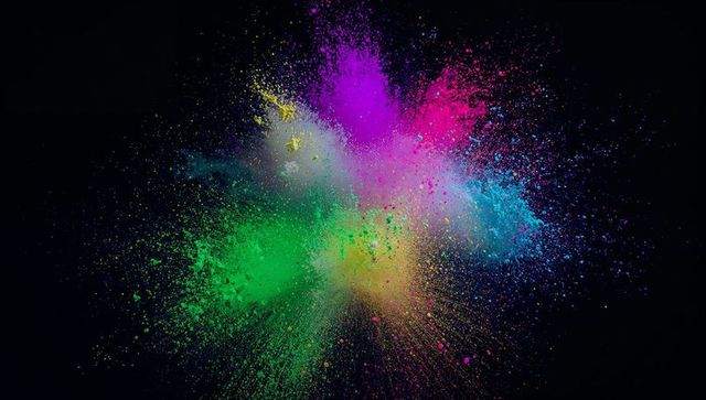 Dynamic multicolored powder explosion against a dark background