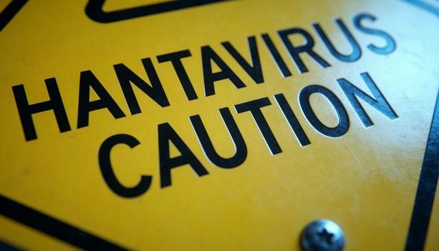 Hantavirus caution warning sign closeup showing yellow hazard placard and mounting screw