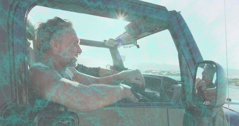 Sunlit man driving jeep along coastal road gripping steering wheel during open-air road trip