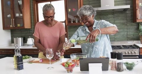 Senior African American Women Enjoying Wine and Cooking in Kitchen