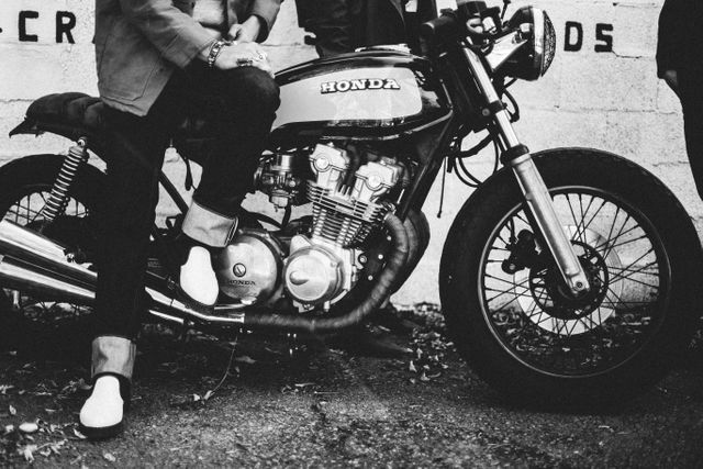Motorcyclist in a classic Honda motorcycle poses in black and white urban scene. Perfect for use in ads targeting motorcycle enthusiasts, retro-themed posters, lifestyle blogs, or street culture magazines.