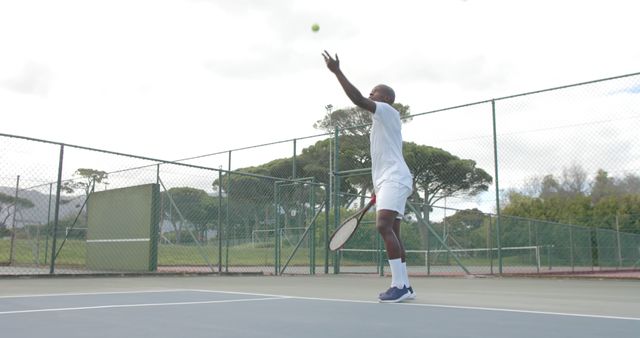 Tennis Player Serving Ball on Outdoor Court Under Clear Sky - Download Free Stock Images Pikwizard.com