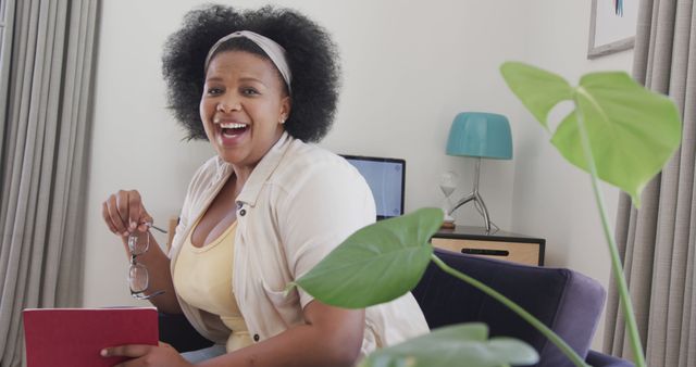 Happy African American Woman Holding Glasses and Smiling at Home Office - Download Free Stock Images Pikwizard.com