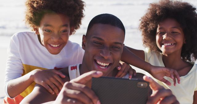 African american father and his children taking a selfie with smartphone on the beach. family outdoor leisure time by the sea.