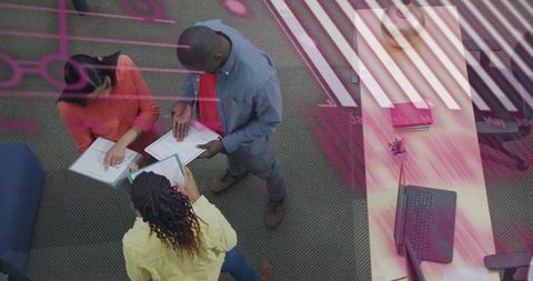 Collaborating over printed documents in open office overhead view with laptop and clipboard