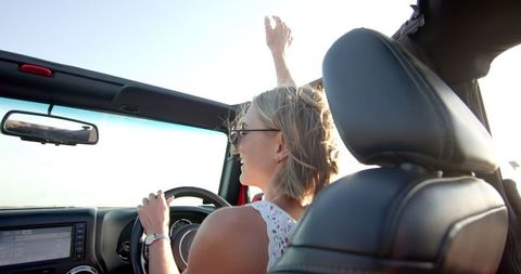 Woman Joyfully Driving Convertible on Sunny Road Trip