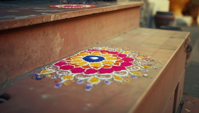 Vibrant rangoli artwork on rustic terracotta step