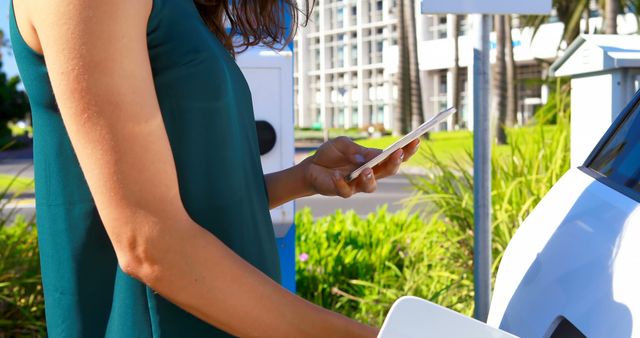 Woman Using Smartphone While Charging Electric Car Outdoors - Download Free Stock Images Pikwizard.com