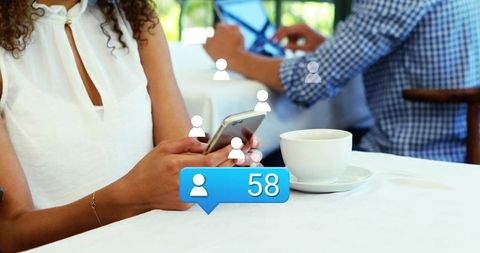 Woman tapping smartphone at cafe holding coffee cup with social follower notification 58