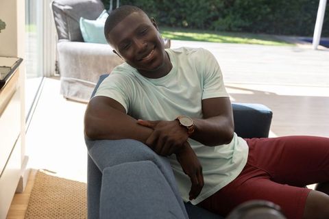 Relaxed African American Man Smiling on Blue Sofa at Home