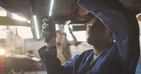 Auto mechanic in garage emphasizing precise under-car repair