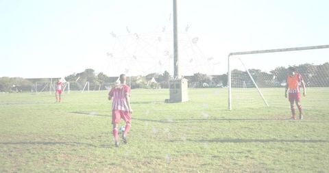 Male soccer players walking on suburban grass field wearing red and white striped jerseys