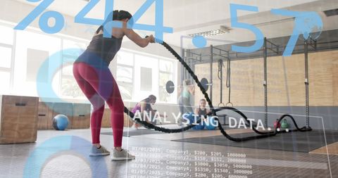 Digital interface overlay on woman exercising with battle ropes at gym