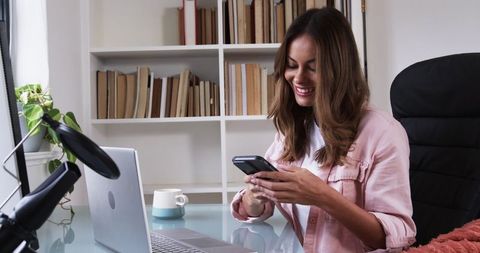 Woman Enjoying a Casual Work-at-Home Setup with Smartphone and Laptop
